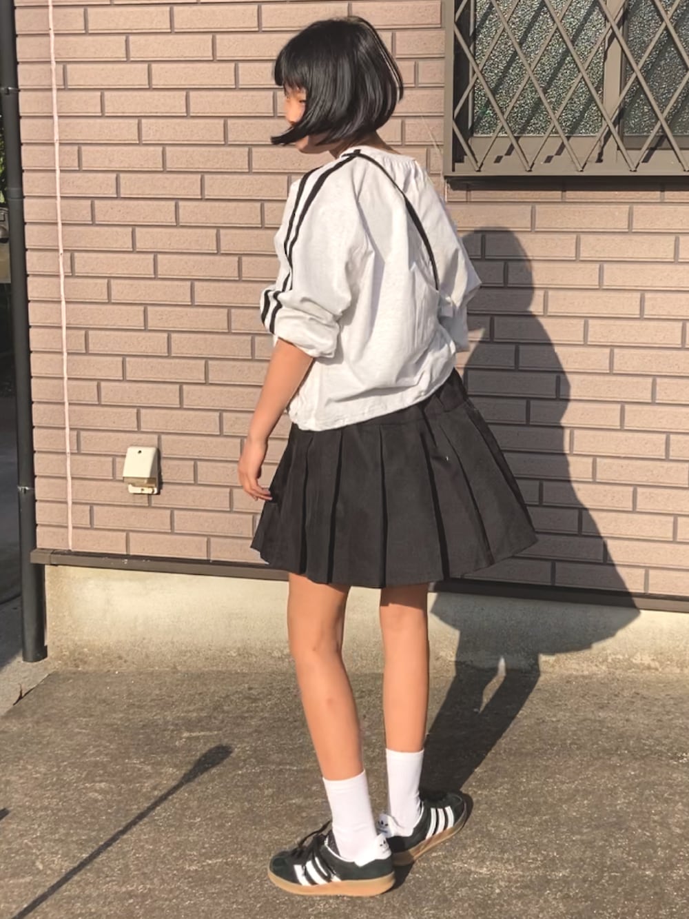 グレー系のTシャツ/カットソー、ブラック系のスカート、ブラック系のスニーカーを着用したキッズの春コーディネートの3枚目の写真