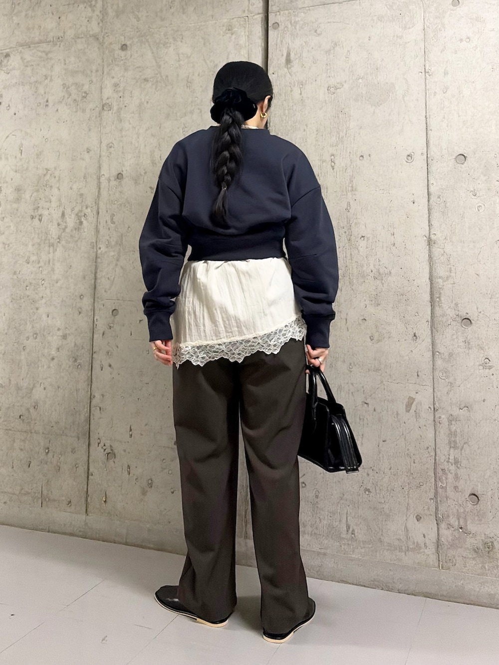 ブラック系のボストンバッグ、ブラック系のパンプス、ブルー系のスウェットを着用したレディースの冬コーディネートの4枚目の写真