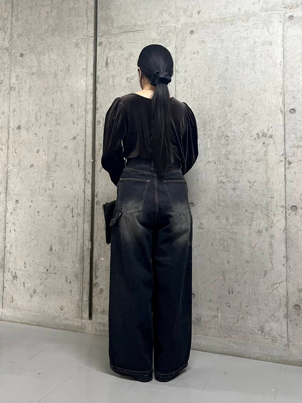 ブラック系のデニムパンツ、ブラウン系のTシャツ/カットソー、ブラック系のボストンバッグを着用したレディースの冬コーディネートの5枚目の写真