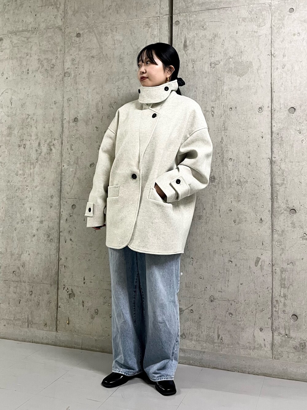 ベージュ系のステンカラーコート、ブルー系のデニムパンツ、ブラック系のその他シューズを着用したレディースの冬コーディネートの5枚目の写真