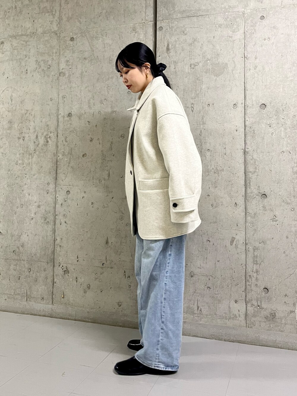 ベージュ系のステンカラーコート、ブルー系のデニムパンツ、ブラック系のその他シューズを着用したレディースの冬コーディネートの3枚目の写真