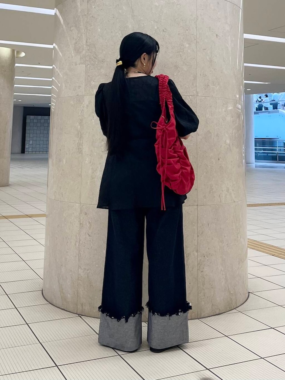 ブラック系のバレエシューズ、ブルー系のデニムパンツ、レッド系のショルダーバッグを着用したレディースの夏コーディネートの3枚目の写真