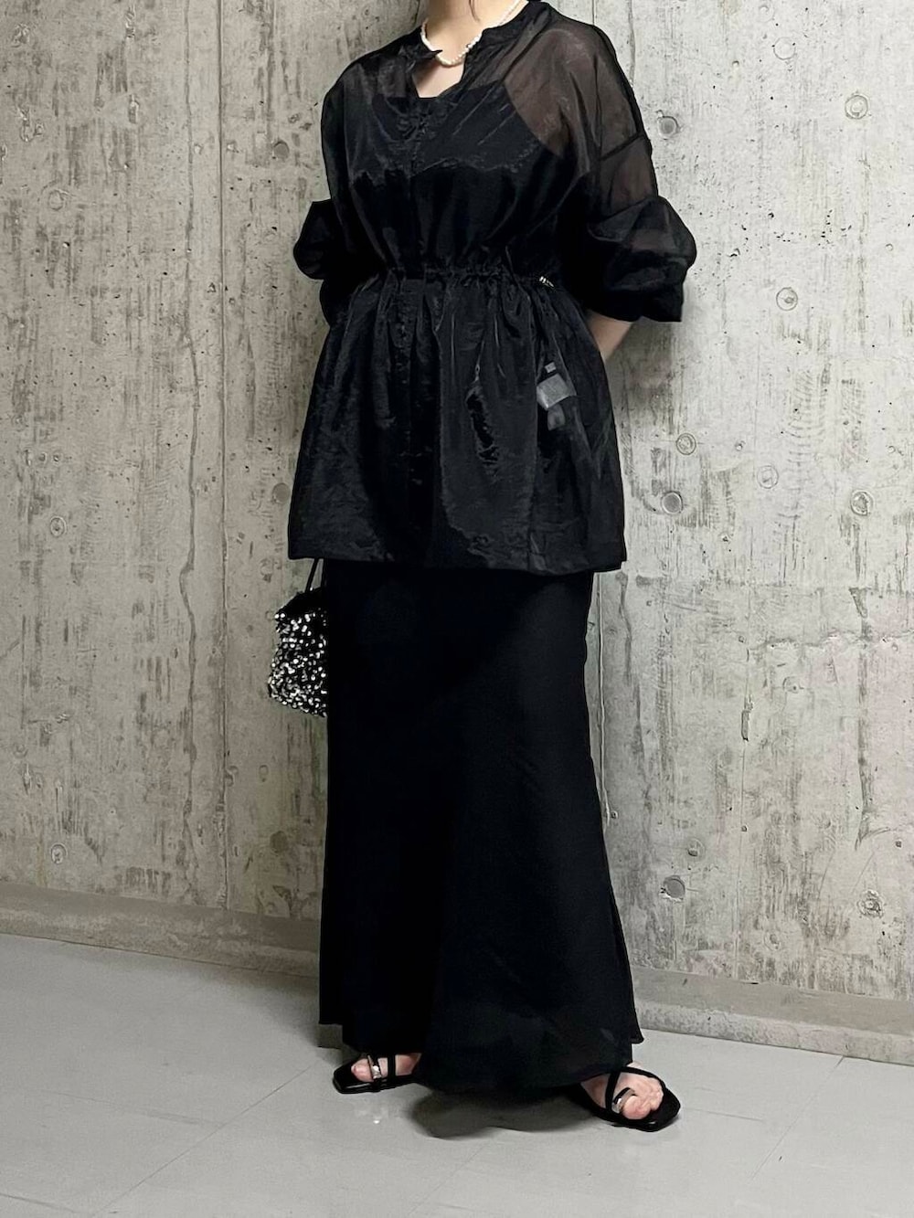 シルバー系のショルダーバッグ、ブラック系のスカート、ブラック系のサンダルを着用したレディースの夏コーディネートの4枚目の写真