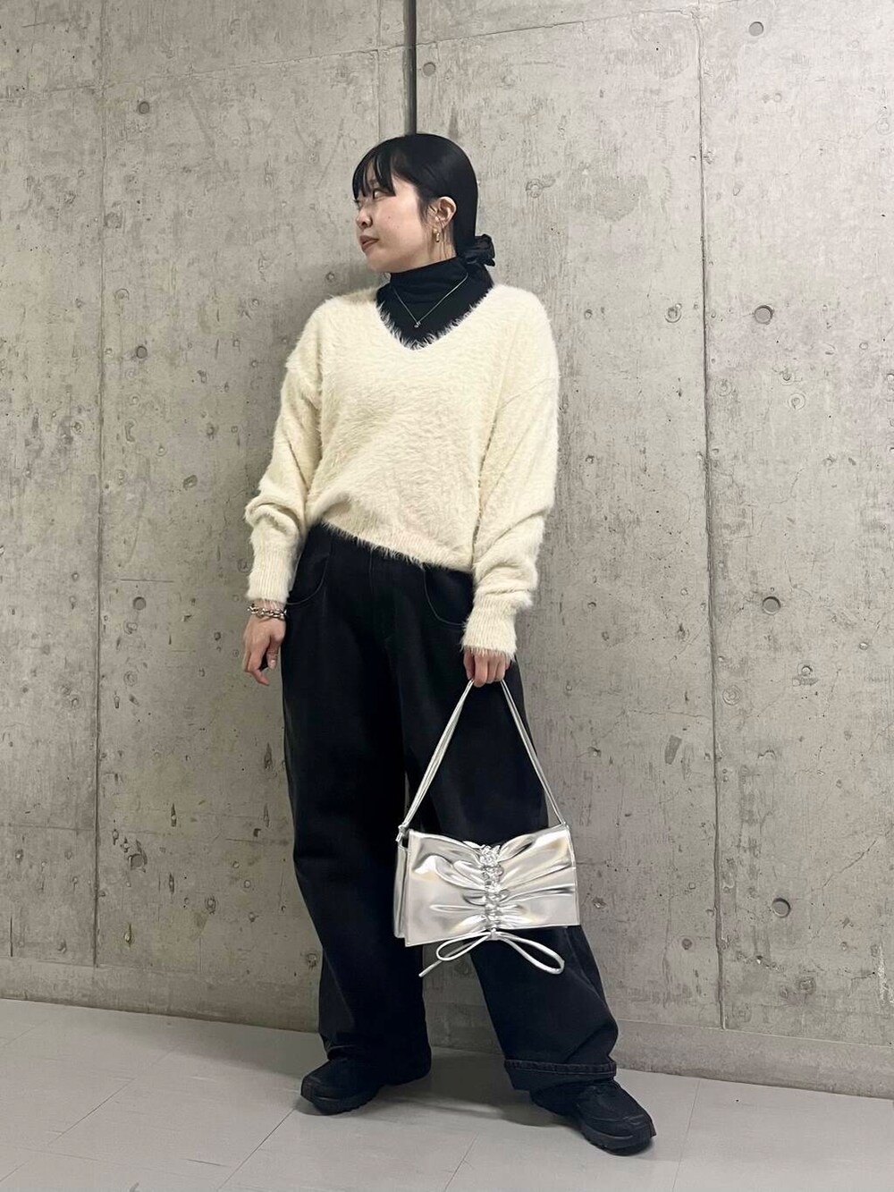 ブラック系のデニムパンツ、シルバー系のショルダーバッグ、ホワイト系のニット/セーターを着用したレディースの冬コーディネートの2枚目の写真