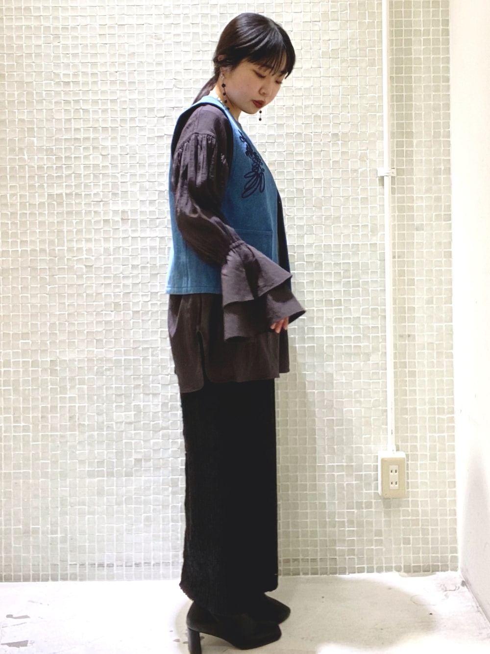 ブラック系のスカート、グレー系のシャツ/ブラウス、ブルー系のベストを着用したレディースの春コーディネートの2枚目の写真