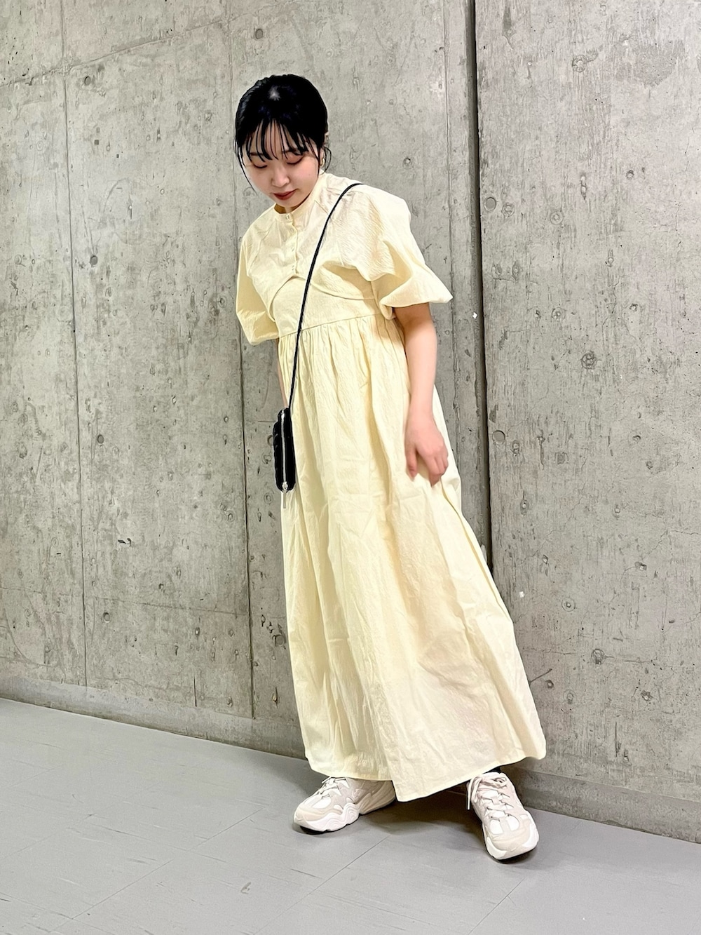ホワイト系のワンピース、ホワイト系のスニーカー、ブラック系のショルダーバッグを着用したレディースの春コーディネートの2枚目の写真
