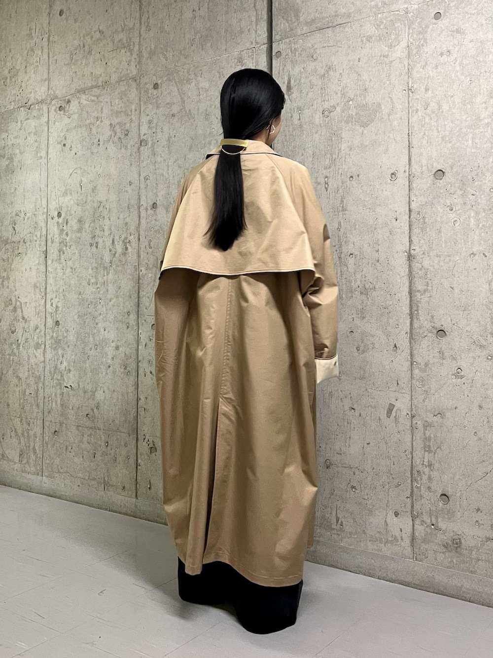 ベージュ系のステンカラーコート、ブラック系のサロペット/オーバーオール、ブラック系のその他シューズを着用したレディースの春コーディネートの3枚目の写真