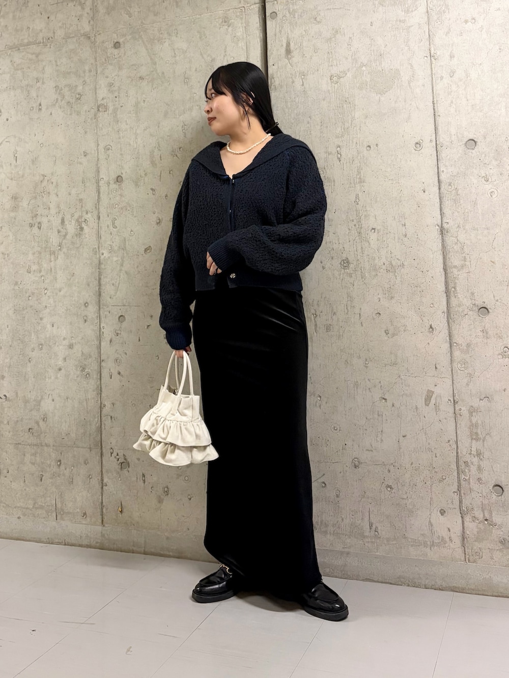 グリーン系のニット/セーター、ブラック系のスカート、ホワイト系のハンドバッグを着用したレディースの冬コーディネートの2枚目の写真
