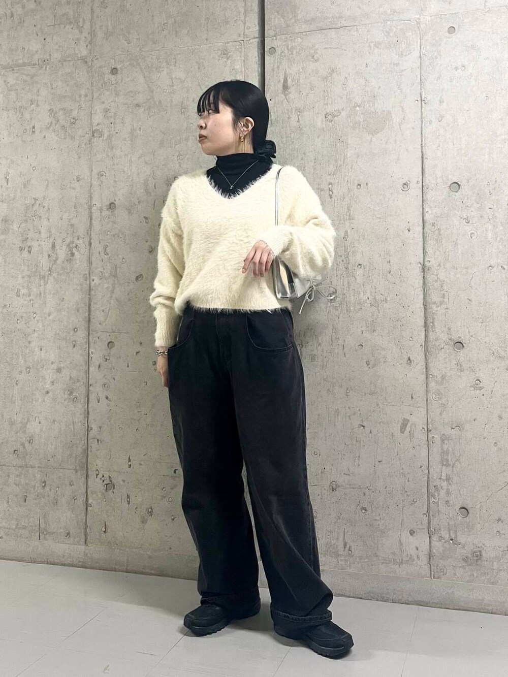 ブラック系のデニムパンツ、シルバー系のショルダーバッグ、ホワイト系のニット/セーターを着用したレディースの冬コーディネートの4枚目の写真