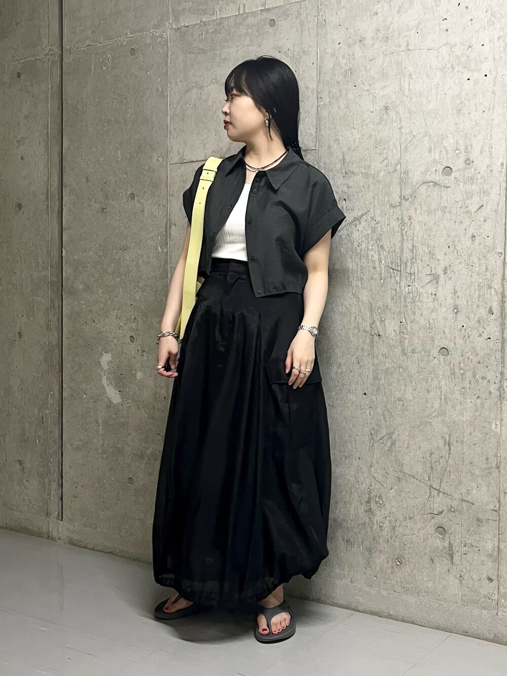 ブラック系のスカート、グレー系のサンダル、イエロー系のショルダーバッグを着用したレディースの夏コーディネートの2枚目の写真
