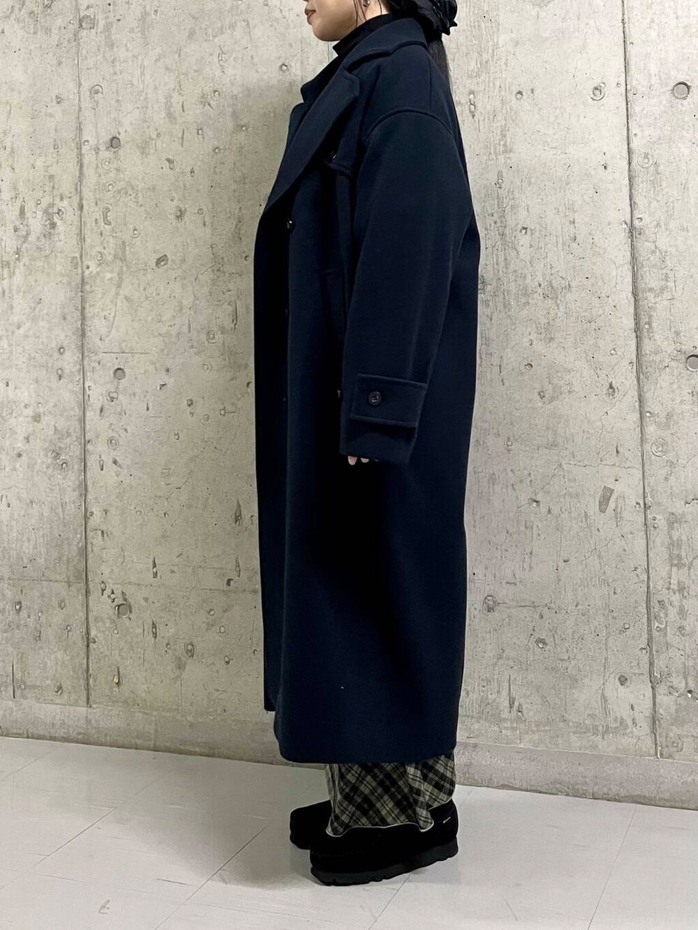 ブルー系のステンカラーコート、ブラック系のカーディガン/ボレロ、グリーン系のスカートを着用したレディースの冬コーディネートの3枚目の写真