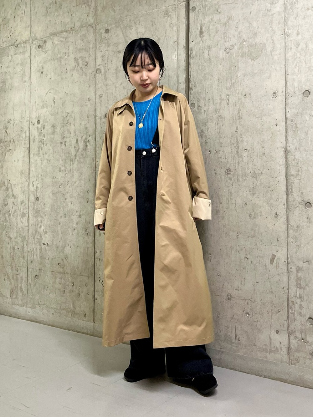 ベージュ系のステンカラーコート、ブラック系のサロペット/オーバーオール、ブラック系のその他シューズを着用したレディースの春コーディネートの4枚目の写真