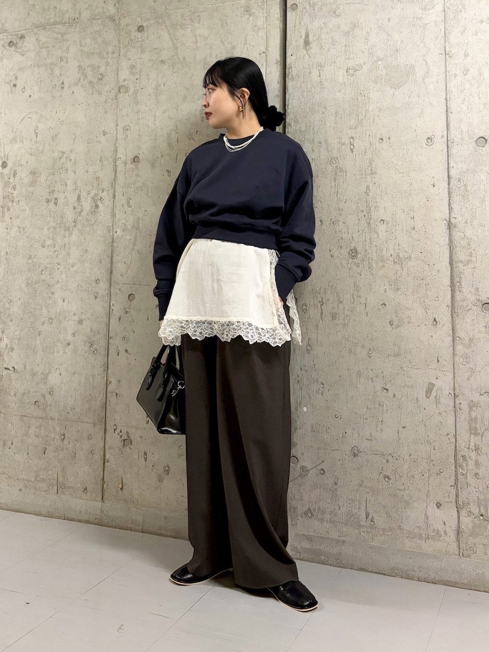 ブラック系のボストンバッグ、ブラック系のパンプス、ブルー系のスウェットを着用したレディースの冬コーディネートの2枚目の写真