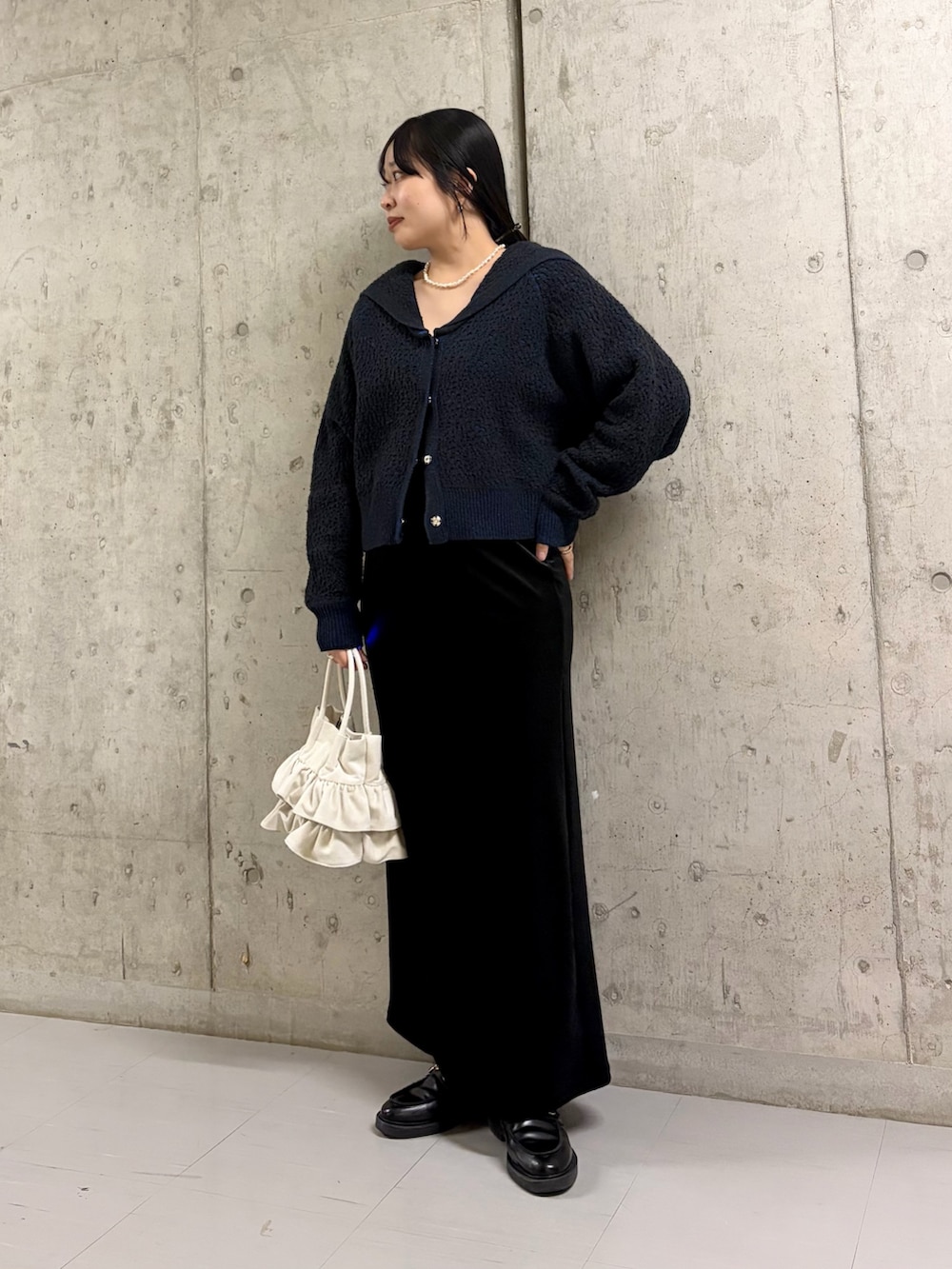 グリーン系のニット/セーター、ブラック系のスカート、ホワイト系のハンドバッグを着用したレディースの冬コーディネートの3枚目の写真