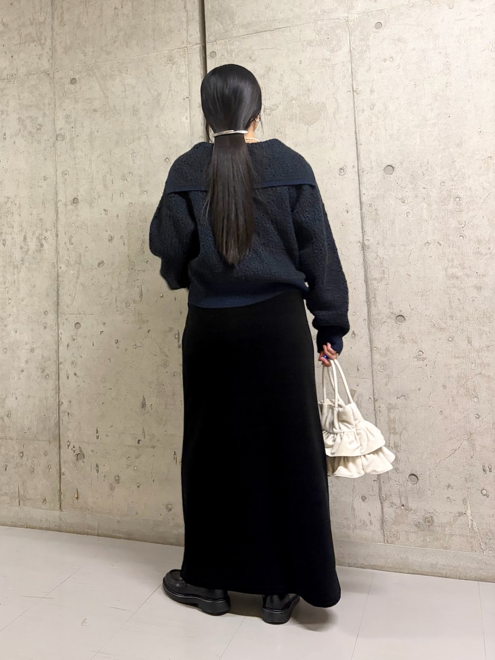 グリーン系のニット/セーター、ブラック系のスカート、ホワイト系のハンドバッグを着用したレディースの冬コーディネートの4枚目の写真