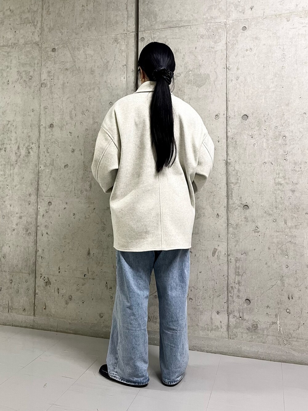 ベージュ系のステンカラーコート、ブルー系のデニムパンツ、ブラック系のその他シューズを着用したレディースの冬コーディネートの2枚目の写真