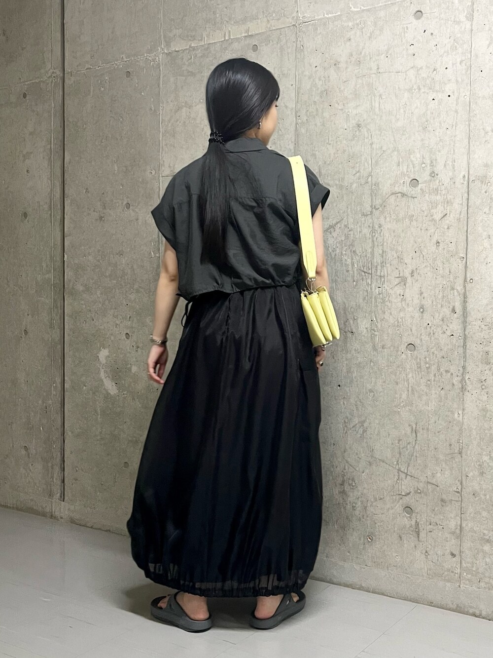 ブラック系のスカート、グレー系のサンダル、イエロー系のショルダーバッグを着用したレディースの夏コーディネートの4枚目の写真