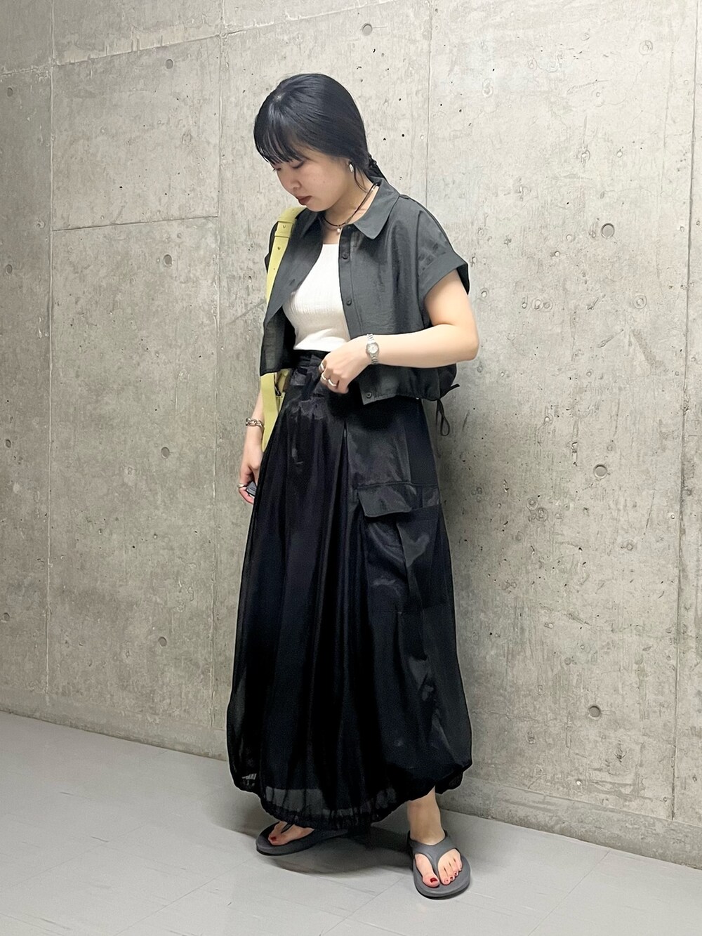 ブラック系のスカート、グレー系のサンダル、イエロー系のショルダーバッグを着用したレディースの夏コーディネートの5枚目の写真