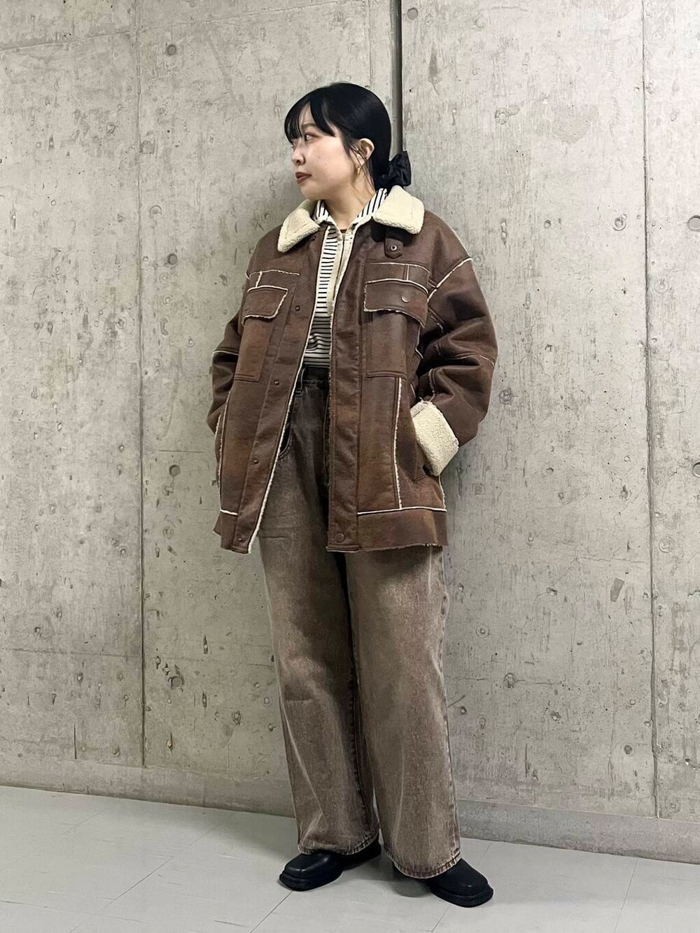 ブラック系のブーツ、ブラウン系のその他アウター、ブラウン系のデニムパンツを着用したレディースの冬コーディネートの2枚目の写真