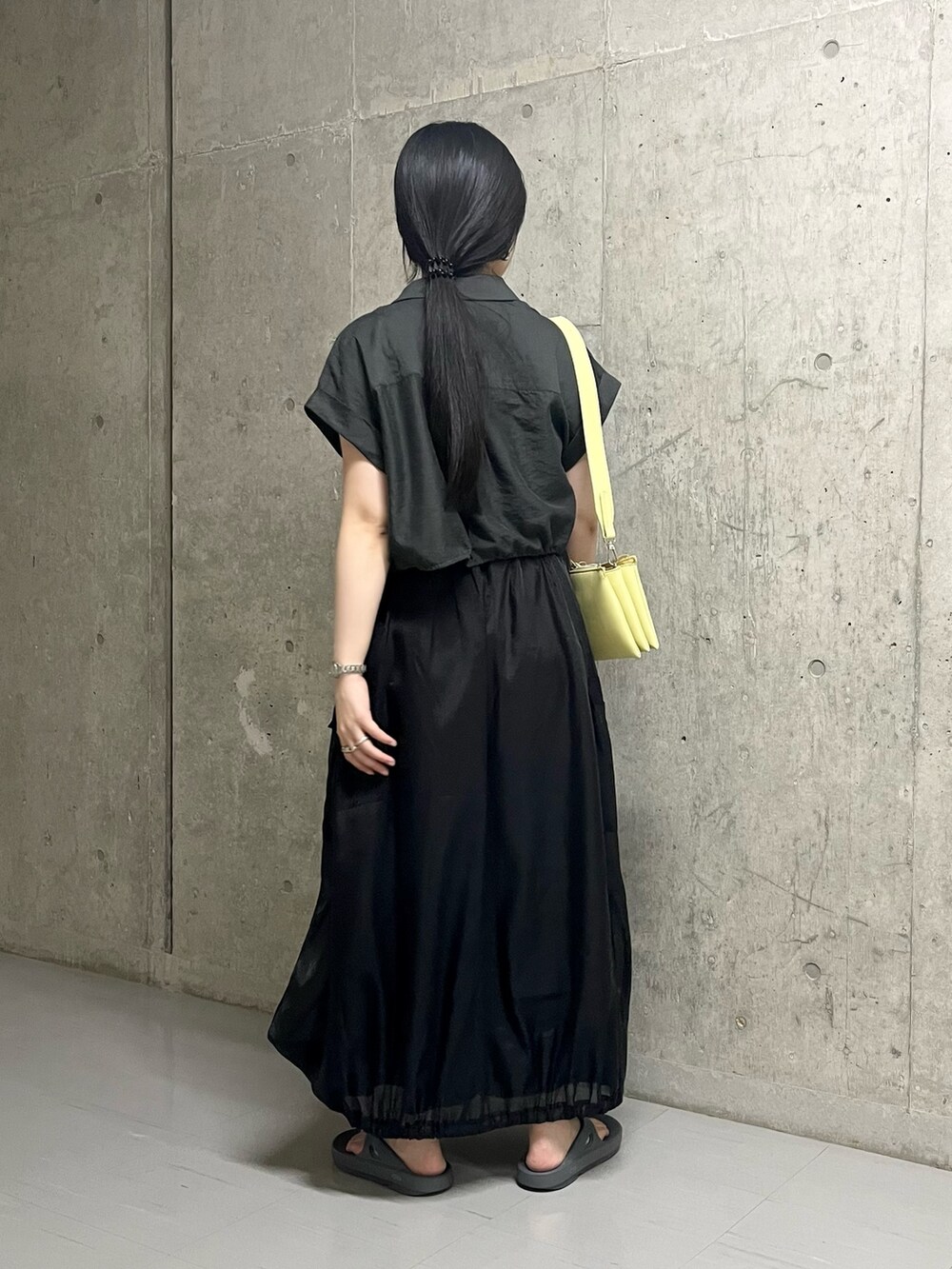 ブラック系のスカート、グレー系のサンダル、イエロー系のショルダーバッグを着用したレディースの夏コーディネートの3枚目の写真