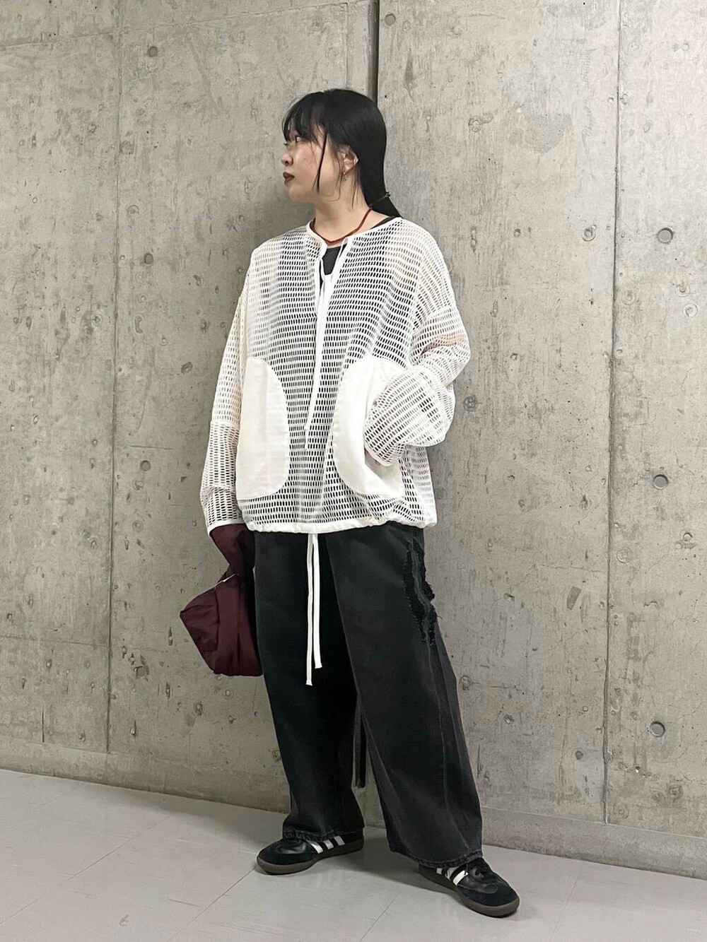 ブラック系のデニムパンツ、レッド系のハンドバッグ、ホワイト系のTシャツ/カットソーを着用したレディースの夏コーディネートの3枚目の写真