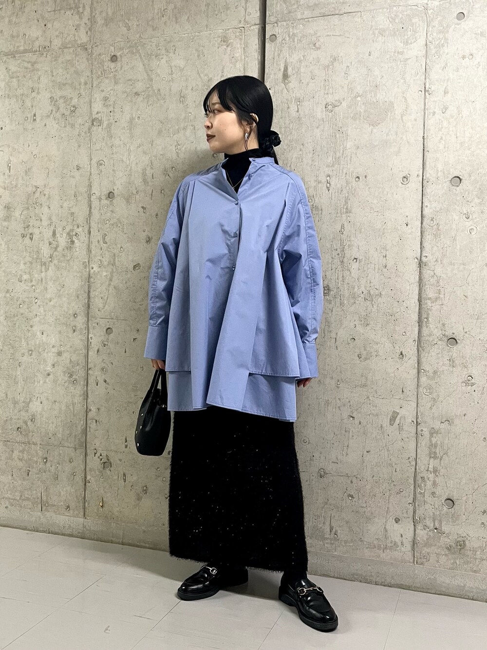 ブルー系のワンピース、ブラック系のスカート、ブラック系のショルダーバッグを着用したレディースの冬コーディネートの2枚目の写真