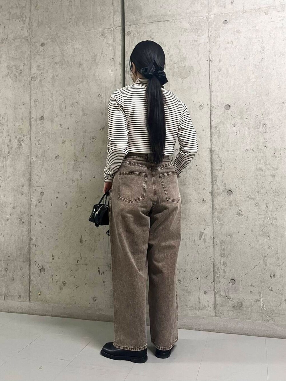 ブラック系のブーツ、ブラウン系のその他アウター、ブラウン系のデニムパンツを着用したレディースの冬コーディネートの6枚目の写真