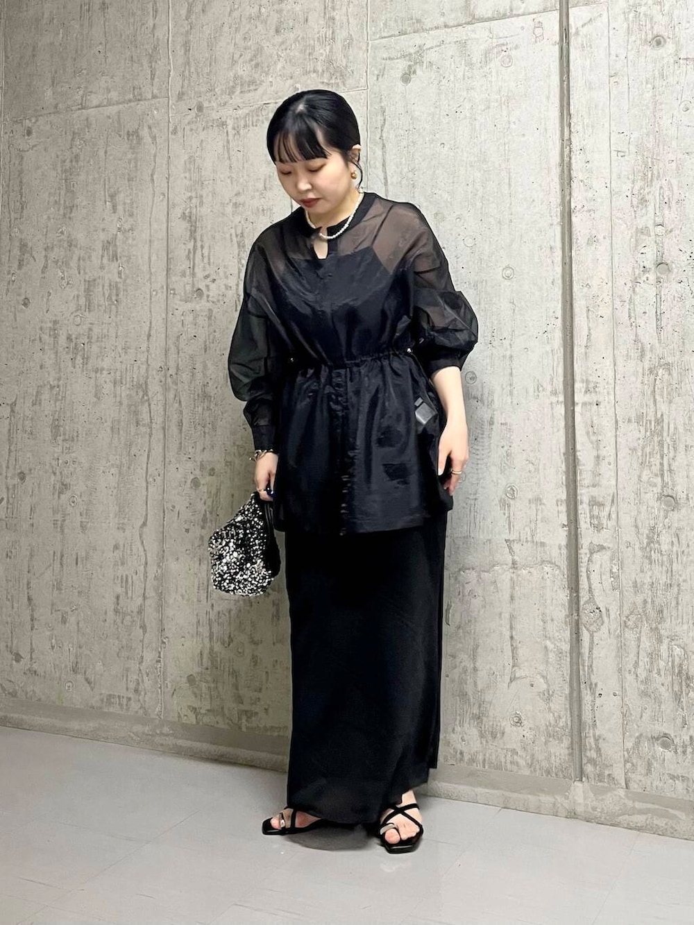 シルバー系のショルダーバッグ、ブラック系のスカート、ブラック系のサンダルを着用したレディースの夏コーディネートの2枚目の写真