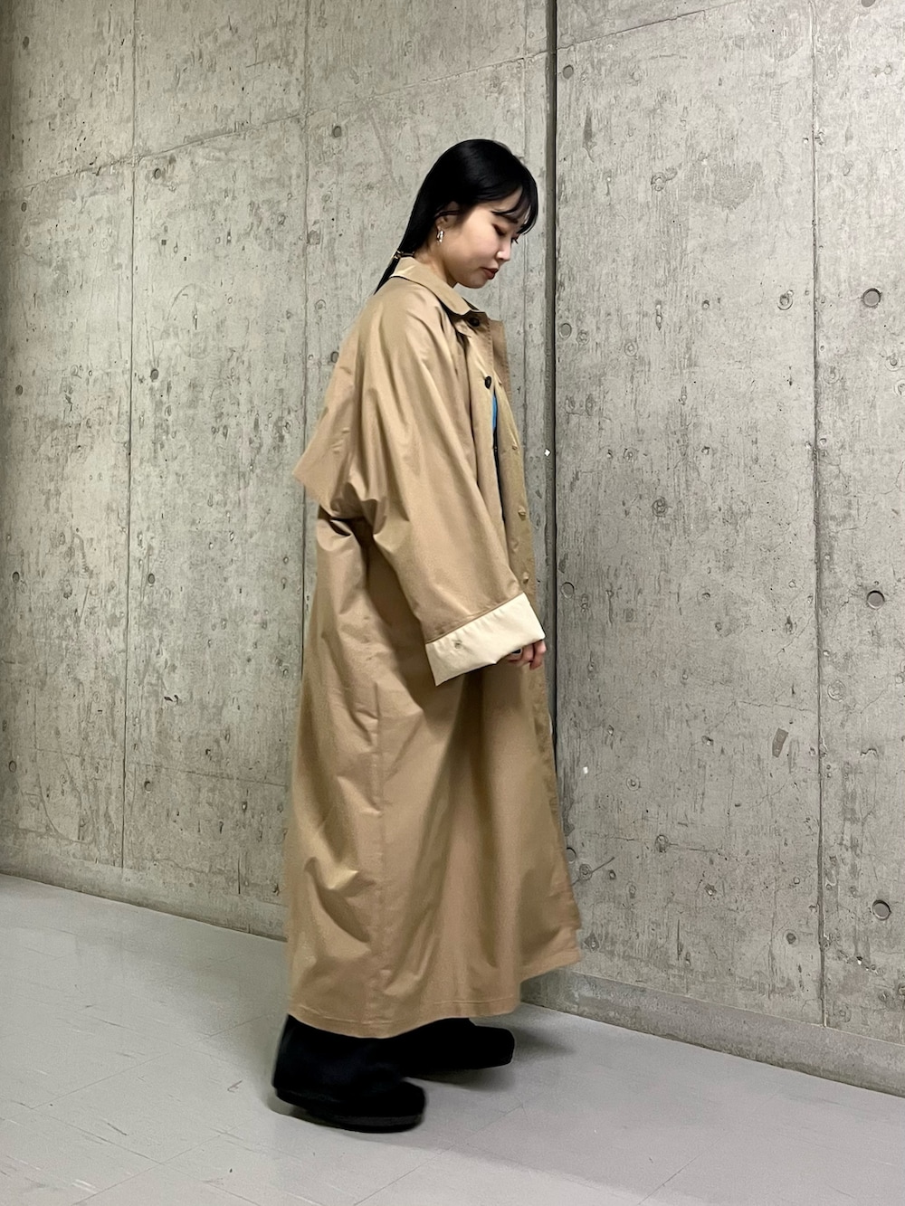 ベージュ系のステンカラーコート、ブラック系のサロペット/オーバーオール、ブラック系のその他シューズを着用したレディースの春コーディネートの2枚目の写真