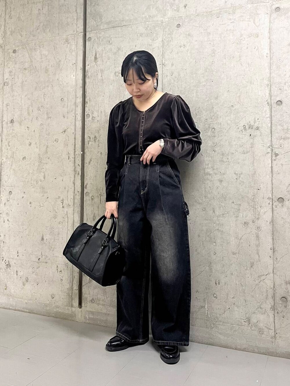 ブラック系のデニムパンツ、ブラウン系のTシャツ/カットソー、ブラック系のボストンバッグを着用したレディースの冬コーディネートの3枚目の写真