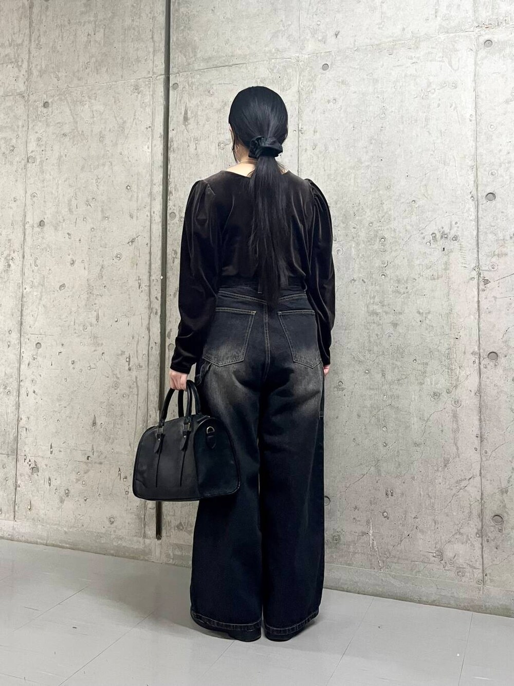 ブラック系のデニムパンツ、ブラウン系のTシャツ/カットソー、ブラック系のボストンバッグを着用したレディースの冬コーディネートの4枚目の写真