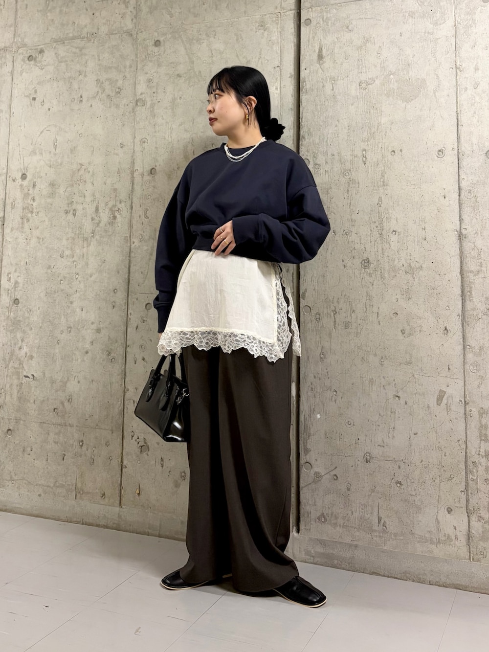 ブラック系のボストンバッグ、ブラック系のパンプス、ブルー系のスウェットを着用したレディースの冬コーディネートの3枚目の写真