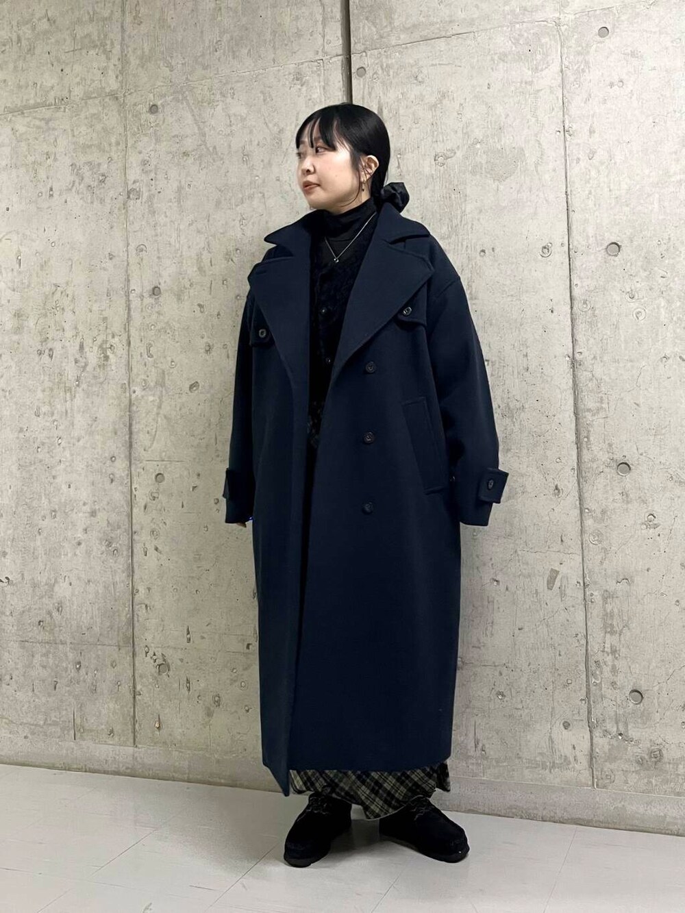 ブルー系のステンカラーコート、ブラック系のカーディガン/ボレロ、グリーン系のスカートを着用したレディースの冬コーディネートの2枚目の写真