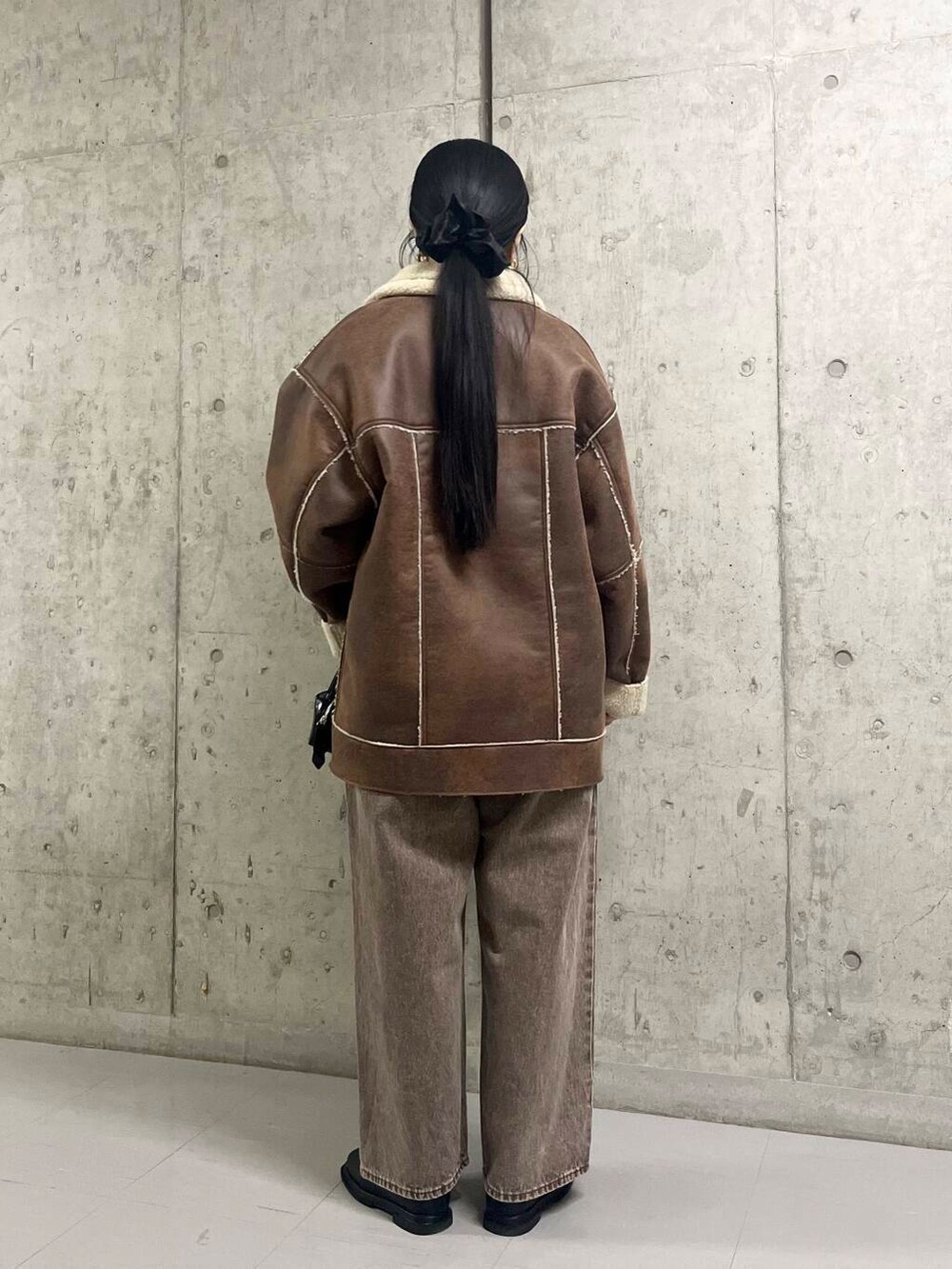 ブラック系のブーツ、ブラウン系のその他アウター、ブラウン系のデニムパンツを着用したレディースの冬コーディネートの3枚目の写真