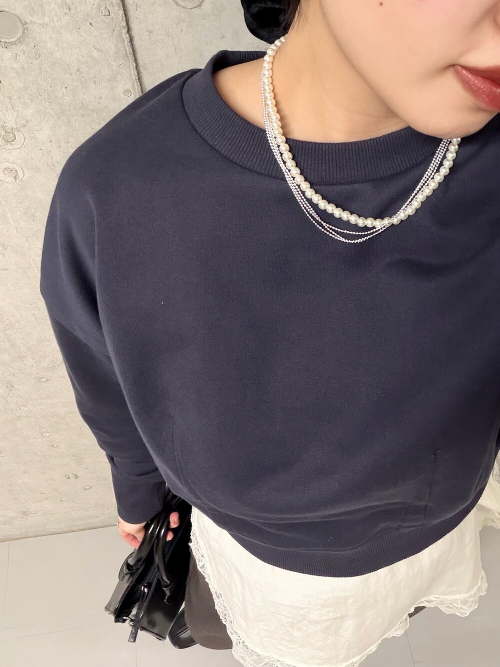 ブラック系のボストンバッグ、ブラック系のパンプス、ブルー系のスウェットを着用したレディースの冬コーディネートの5枚目の写真