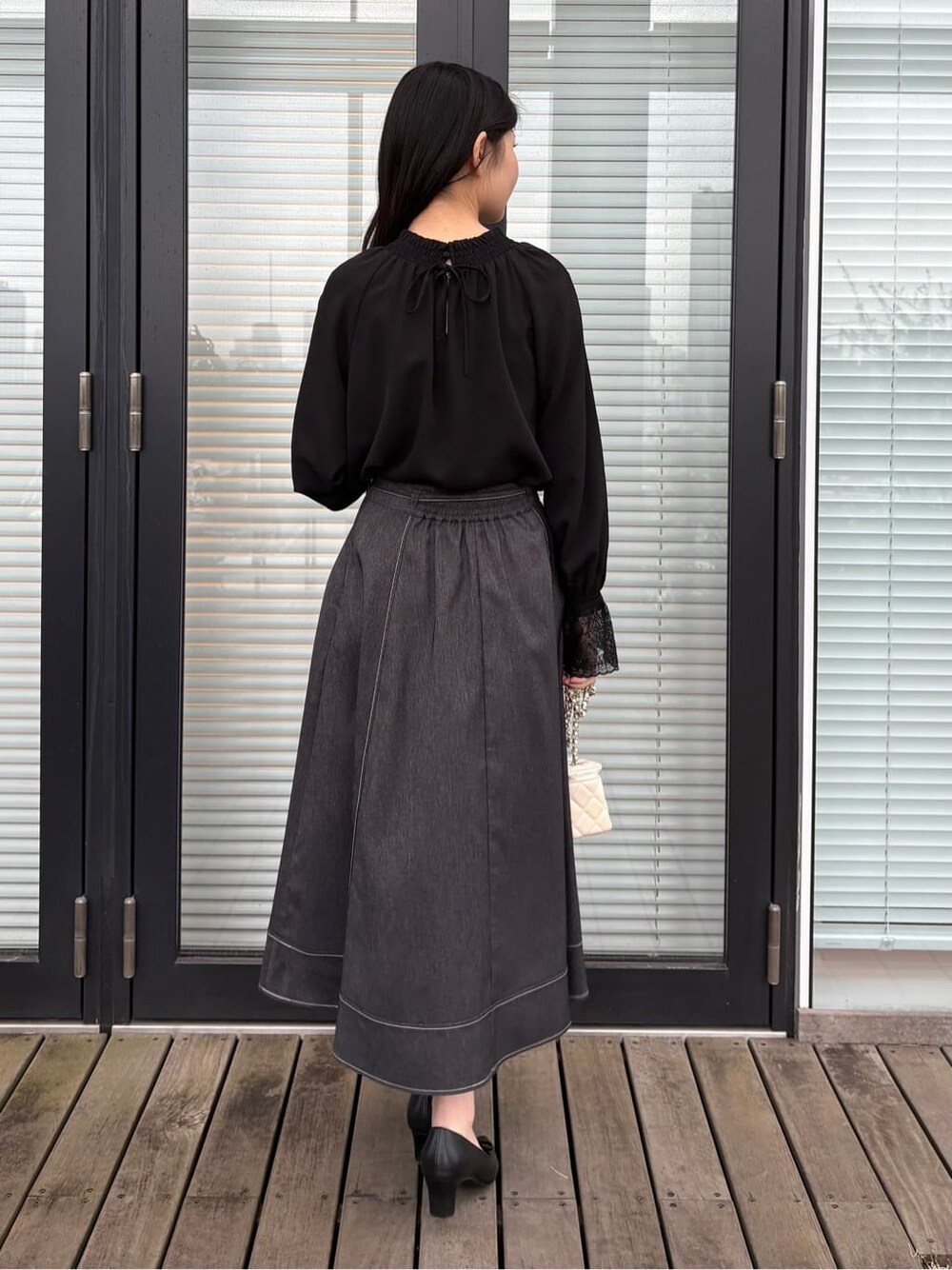 ブラック系のシャツ/ブラウス、ブラック系のスカート、ブラック系のパンプスを着用したレディースの春コーディネートの4枚目の写真