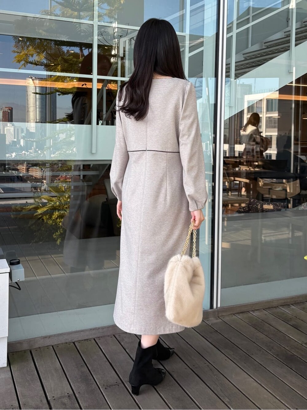 グレー系のワンピース、ホワイト系のトートバッグ、ブラック系のブーツを着用したレディースの冬コーディネートの4枚目の写真