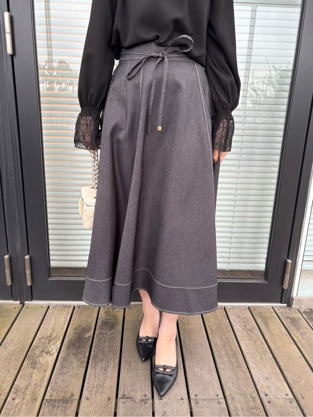 ブラック系のシャツ/ブラウス、ブラック系のスカート、ブラック系のパンプスを着用したレディースの春コーディネートの6枚目の写真