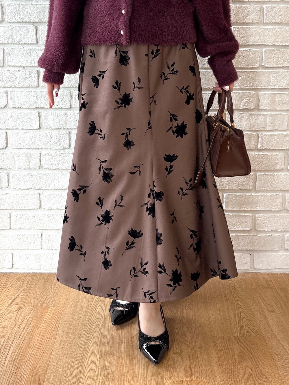 レッド系のカーディガン/ボレロ、ブラウン系のスカート、ブラック系のパンプスを着用したレディースの秋コーディネートの5枚目の写真