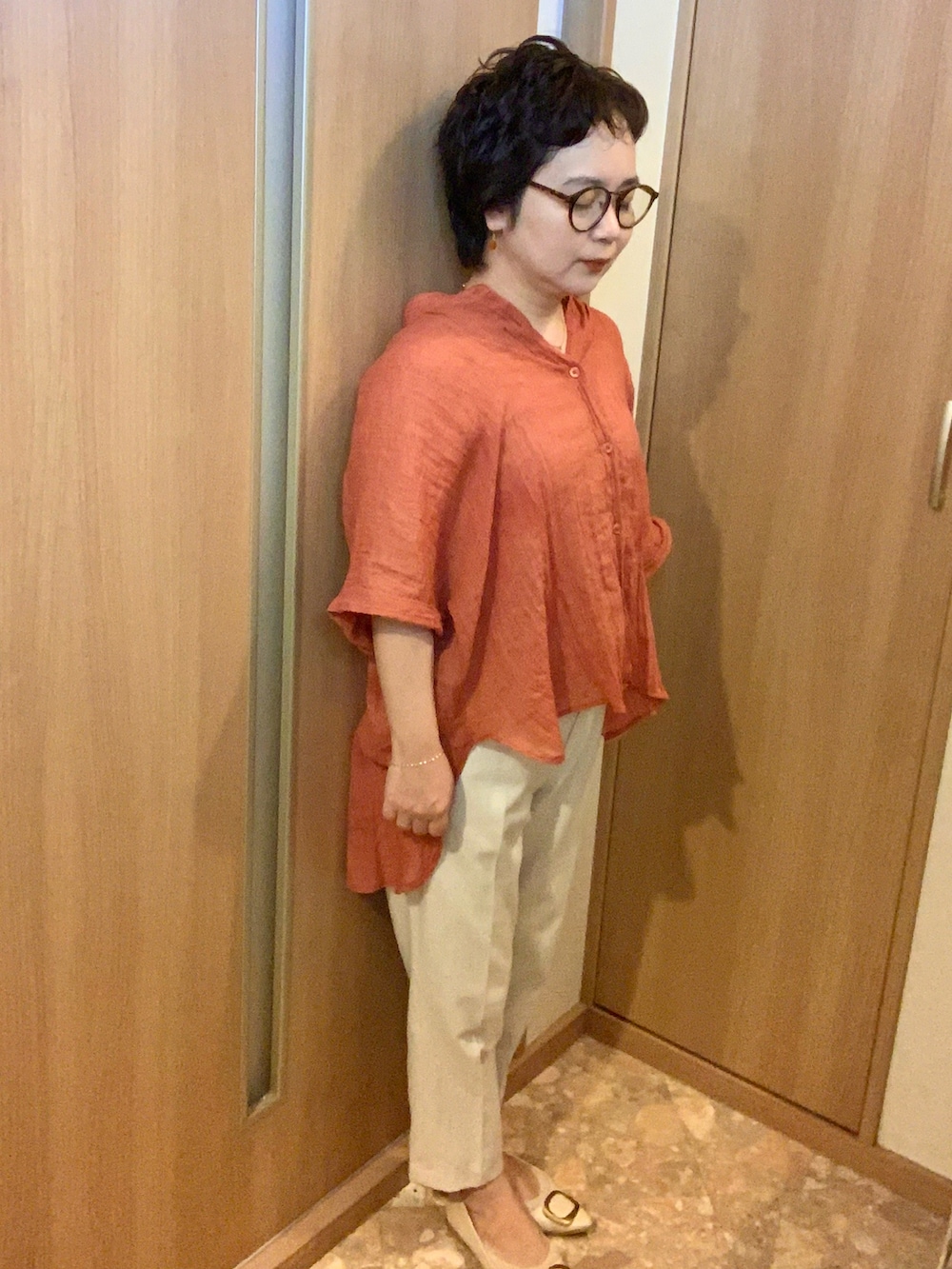 ホワイト系のパンプス、ブラック系のバックパック/リュック、オレンジ系のシャツ/ブラウスを着用したレディースの夏コーディネートの2枚目の写真
