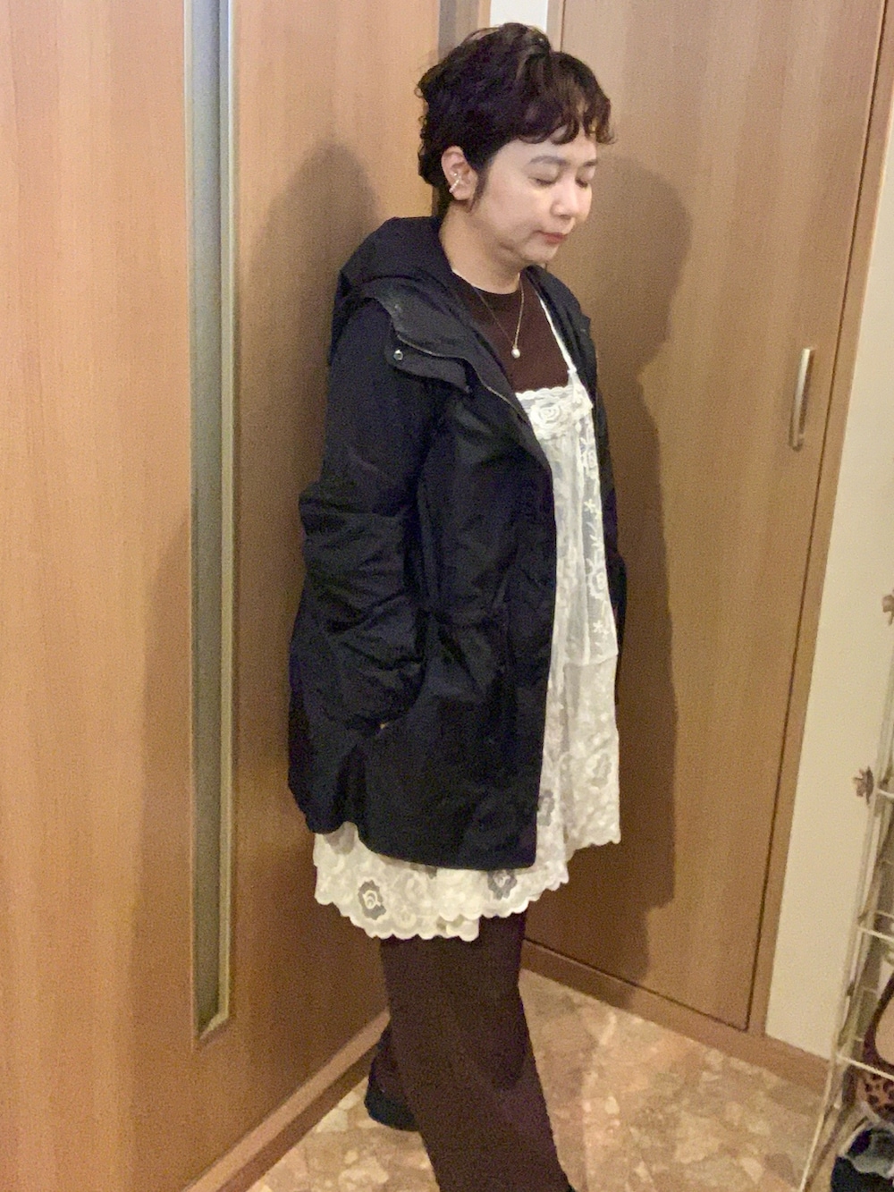 ホワイト系のチュニック、ブラウン系のパンツ、ブラック系のスニーカーを着用したレディースの秋コーディネートの2枚目の写真