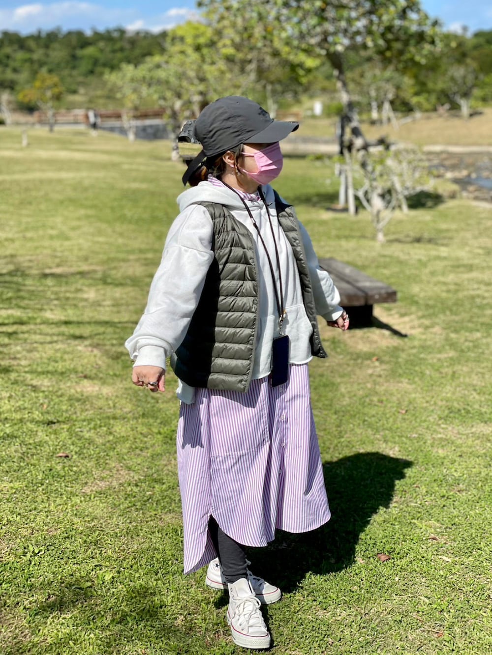 ホワイト系のスニーカー、ピンク系のシャツワンピース、ホワイト系のパーカーを着用したレディースの春コーディネートの3枚目の写真