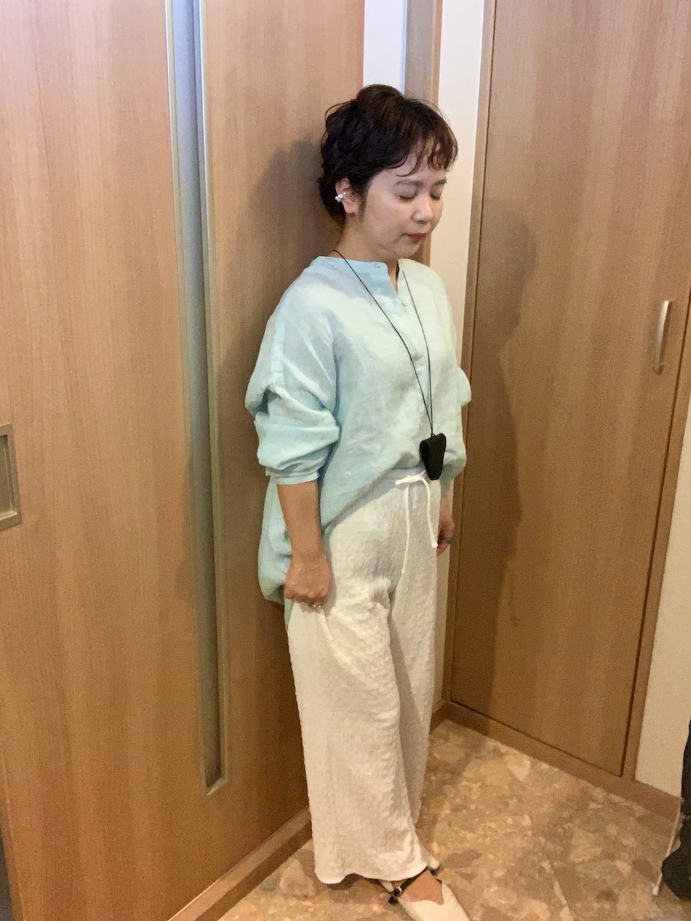 ホワイト系のパンツ、ホワイト系のパンプス、グリーン系のシャツ/ブラウスを着用したレディースの秋コーディネートの2枚目の写真