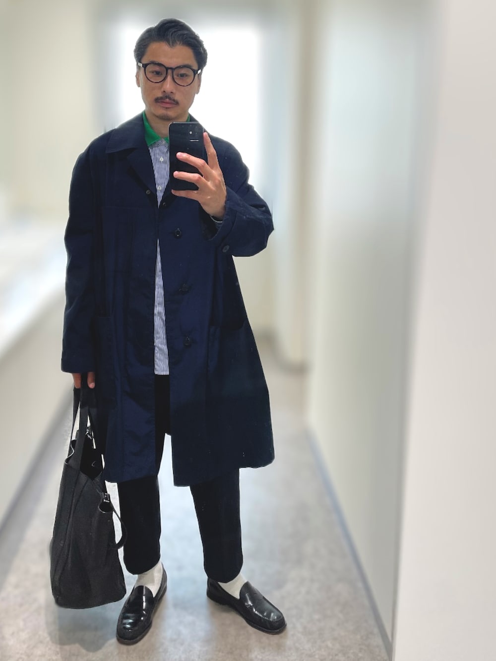 ブルー系のステンカラーコート、ブラック系のローファー、ブルー系のチノパンツを着用したメンズの春コーディネートの2枚目の写真