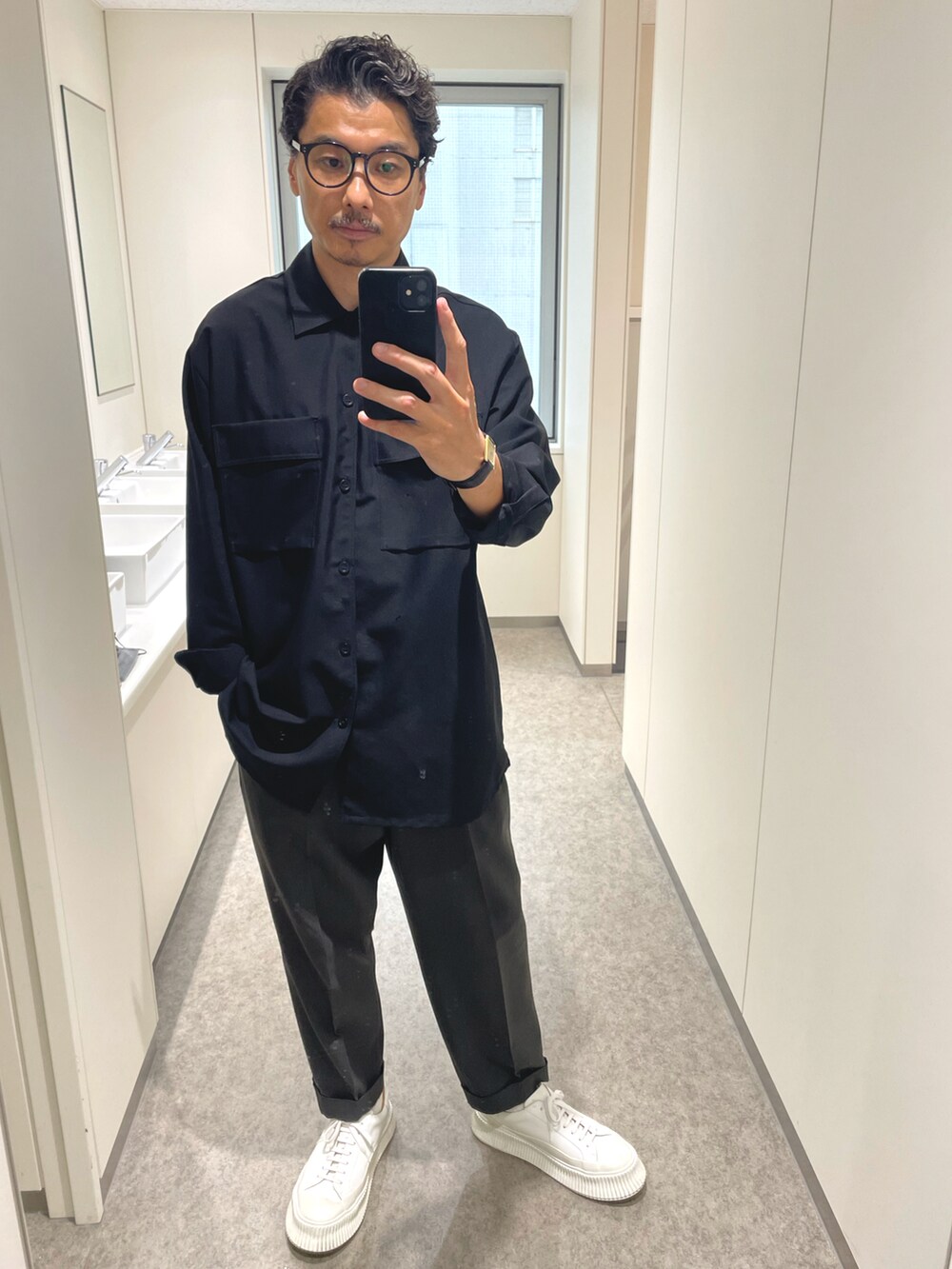 ブラック系のトートバッグ、ホワイト系のスニーカー、グレー系のスラックスを着用したメンズの秋コーディネートの2枚目の写真