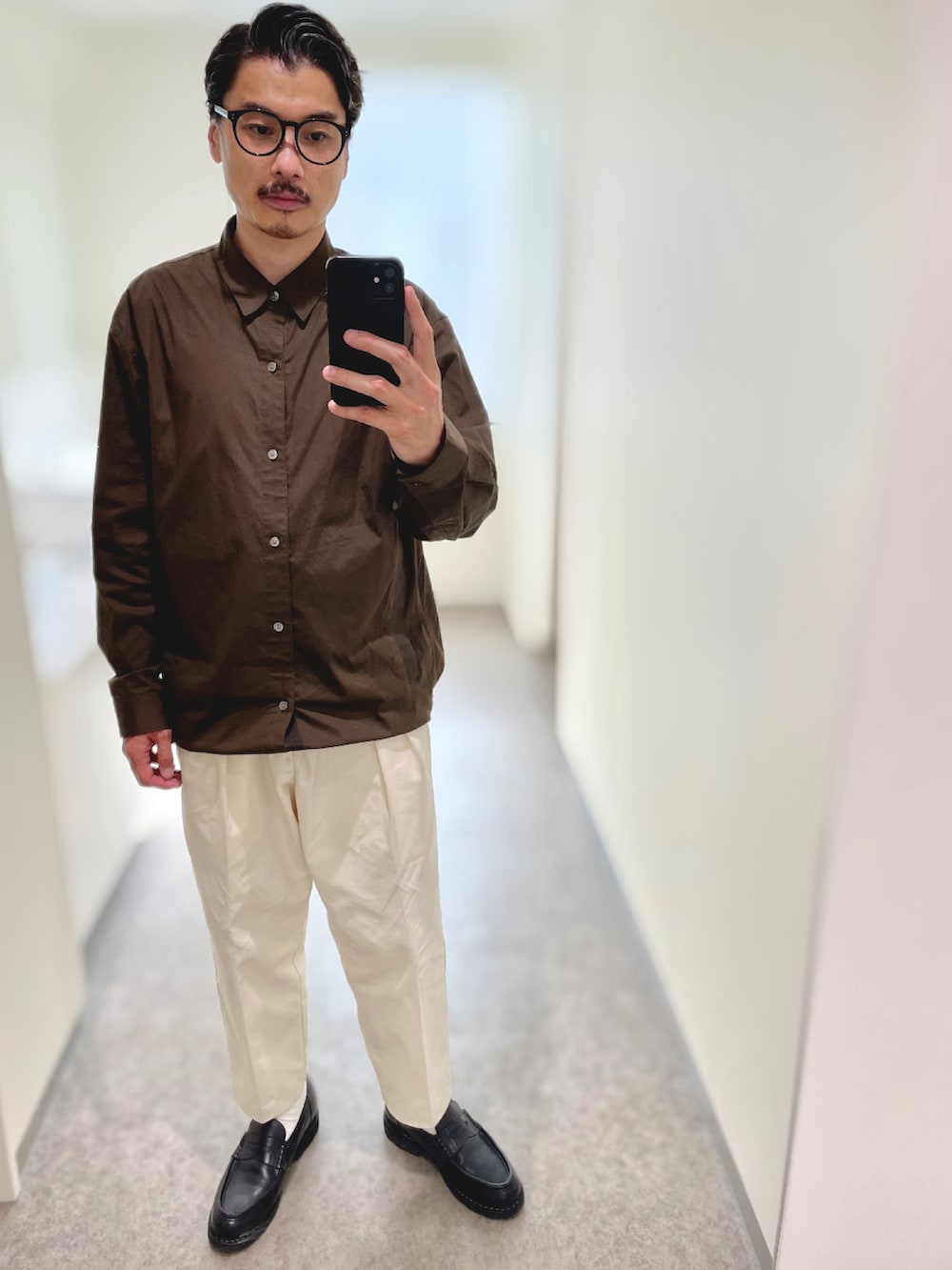 ブラック系のトートバッグ、ブラック系のドレスシューズ、ベージュ系のチノパンツを着用したメンズの春コーディネートの3枚目の写真