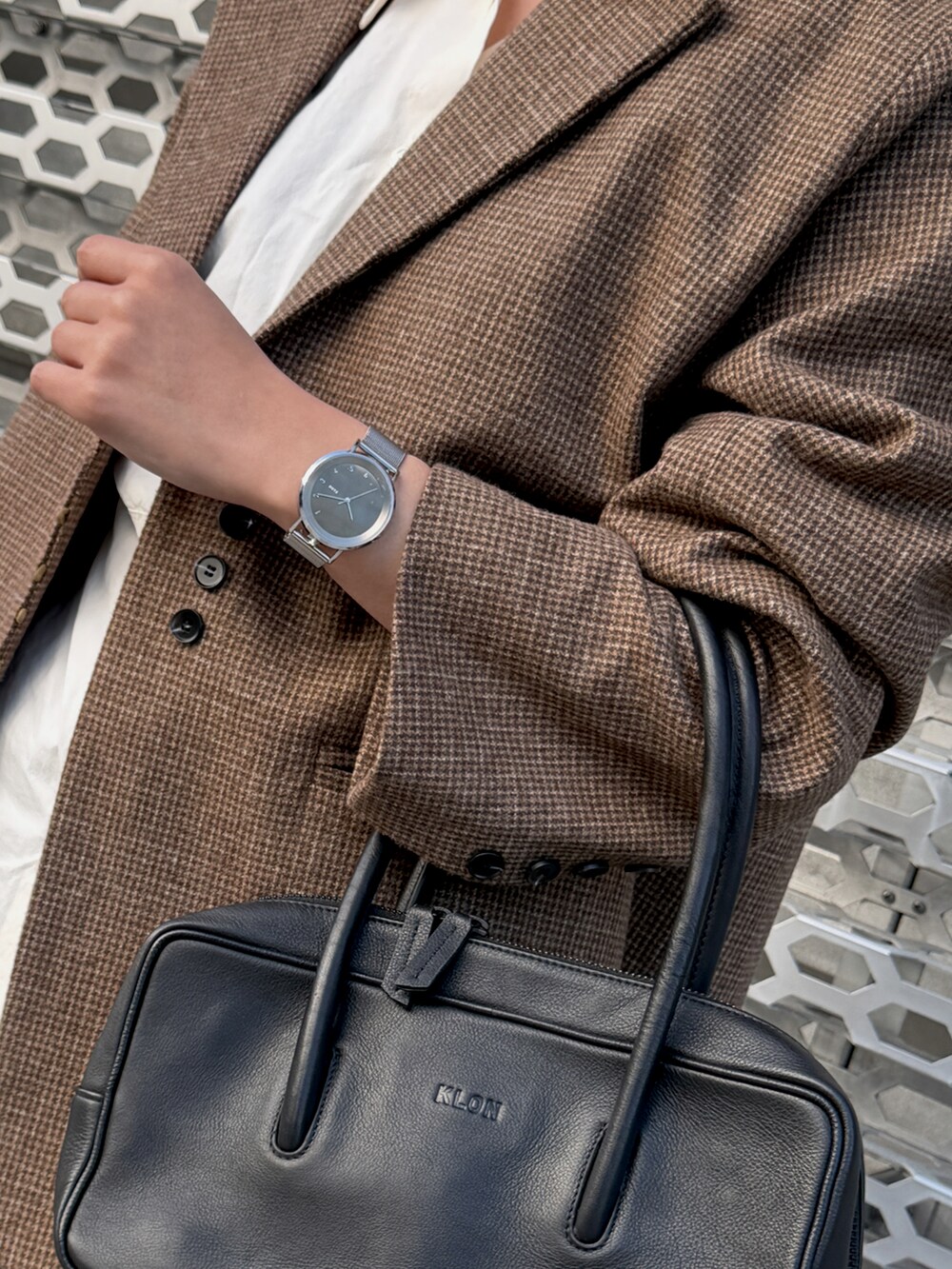 ブラック系のハンドバッグ、シルバー系のアナログ腕時計を着用したレディースの冬コーディネートの3枚目の写真