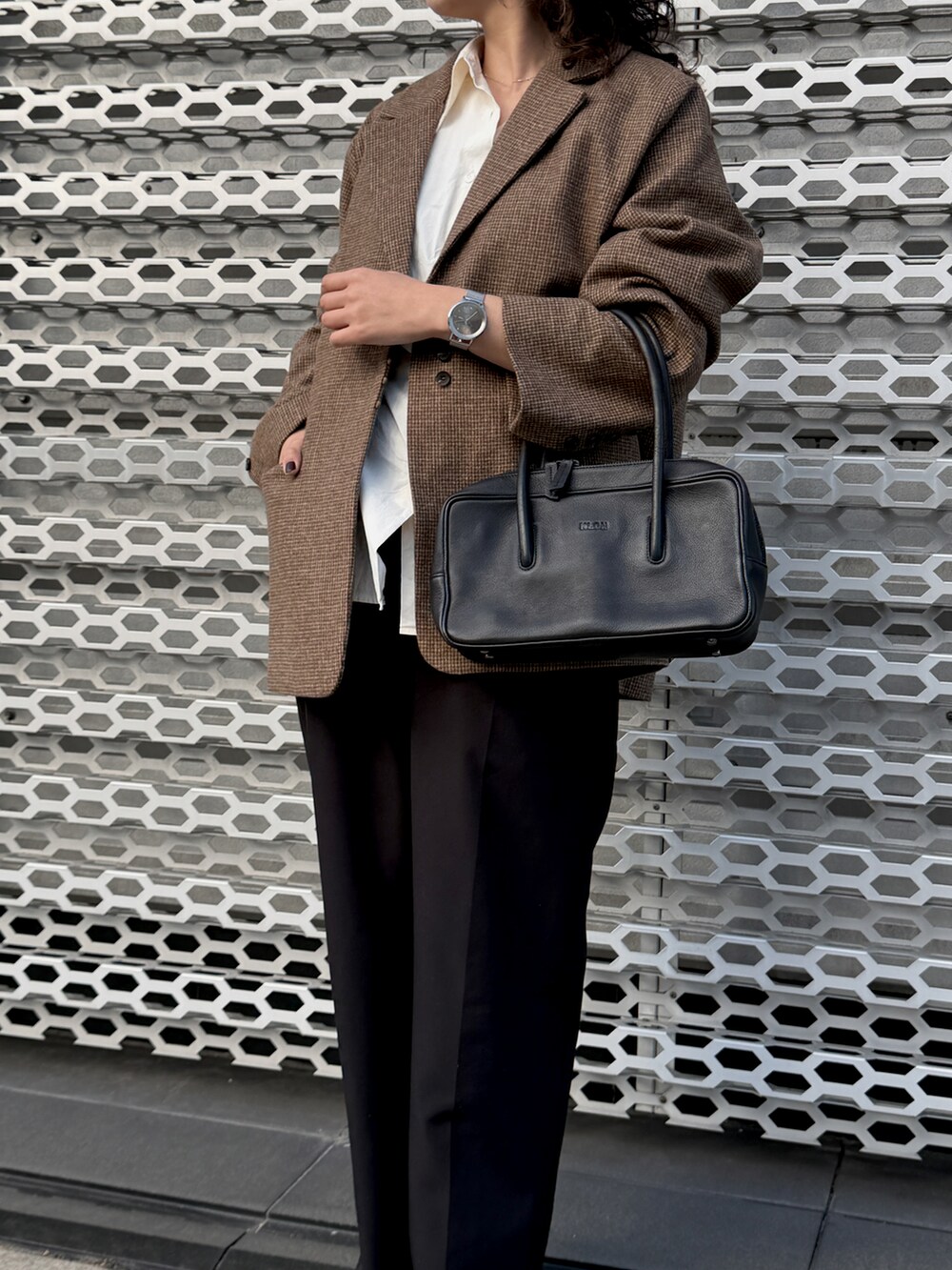 ブラック系のハンドバッグ、シルバー系のアナログ腕時計を着用したレディースの冬コーディネートの2枚目の写真