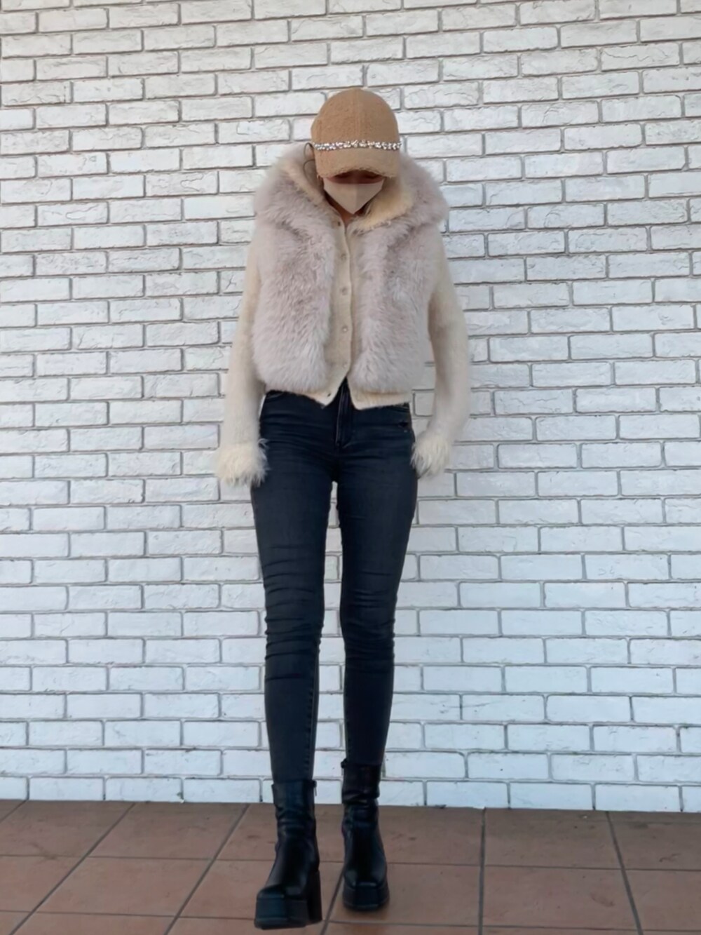 ブラック系のバッグ、ホワイト系のベスト、ブラック系のブーティを着用したレディースの冬コーディネートの2枚目の写真