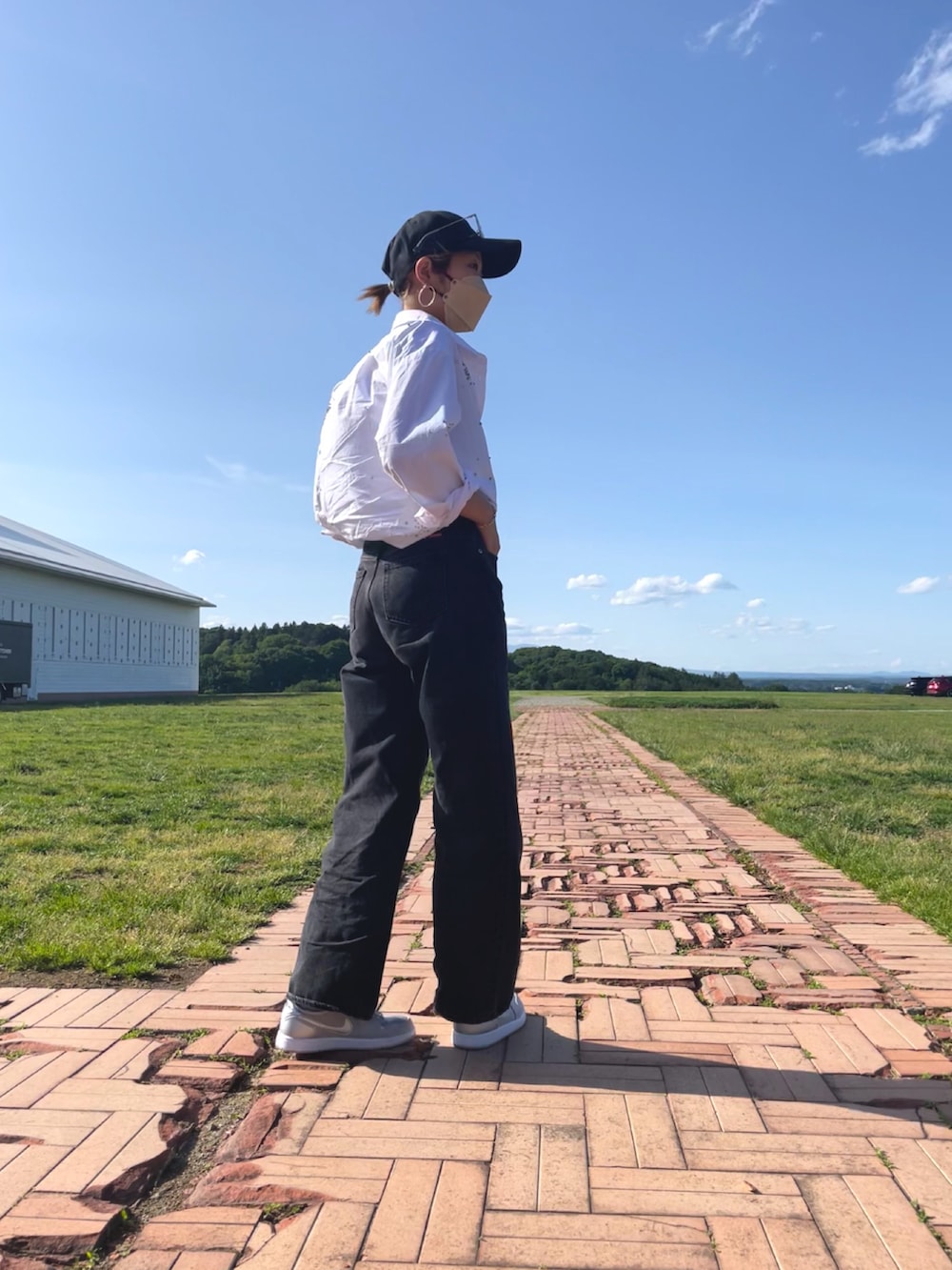 ホワイト系のシャツ/ブラウス、ブラック系のデニムパンツ、シルバー系のスニーカーを着用したレディースの春コーディネートの2枚目の写真